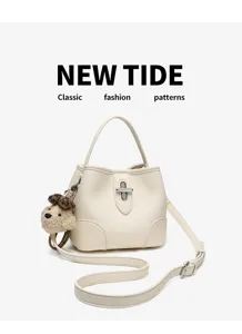 Detail view of the white leather bucket bag featuring a metal lock and cute plush dog charm.