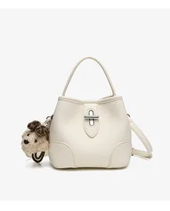 Details of white leather bucket bag with metal lock closure and cute puppy pendant.