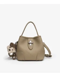 Minimalist leather bucket bag with top handle, crossbody strap and cute bear charm.
