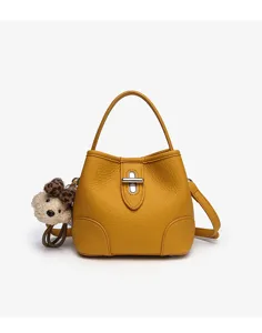 Detailed view of yellow pebble leather bucket bag with metal turn-lock and cute bear charm.