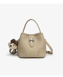 Beige leather bucket bag with top handle, metal turn-lock closure and cute bear pendant.