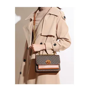 Close-up of retro monogram shoulder bag with chic camellia metal clasp and chain.