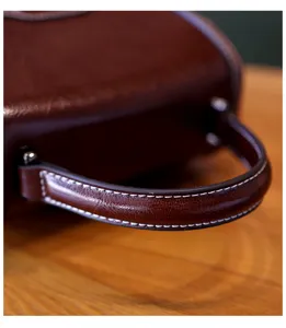 Close-up detail view of vintage brown leather handbag handle with exquisite white stitching.