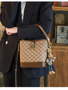 Fashionable monogram bucket bag with leather trim, metal lock and plush rabbit charm.