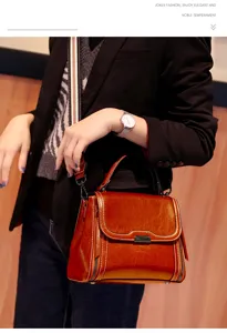 Brown vintage leather top handle handbag detail showing texture and metal hardware.