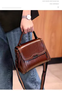 Close-up detail of the retro brown leather handbag with metal buckle and shoulder strap.