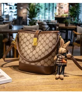 Detailed view of stylish printed bucket bag with brown leather trim and cute rabbit pendant charm.