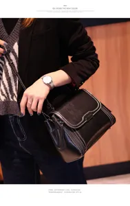 Black leather shoulder bag with white contrast stitching and chic metal closure for women.