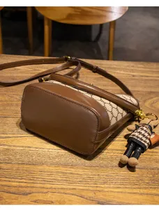 Brown and beige printed bucket bag with chic monogram canvas, PU leather trim and doll charm.
