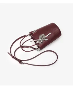Wine red mini bucket bag detail view, chic leather crossbody bag with silver charm pendant.