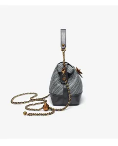 Grey woven shell crossbody bag detail view with chain strap and camellia flower decoration.