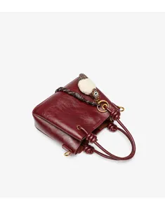 Elegant retro red leather handbag with braided rope and cute charm detail, stylish daily purse.