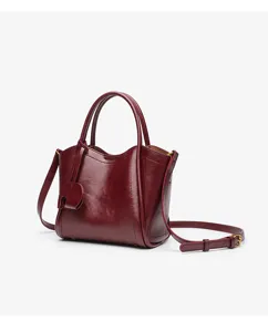 Red leather handbag detail, featuring fine stitching, elegant folded sides and polished hardware.