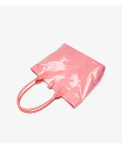 Detail view of pink glossy DuPont paper tote bag showing texture, handles and snap closure.