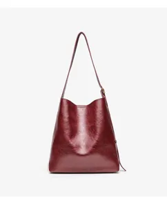 Detailed closeup view of dark red leather shoulder bag, premium textured surface, minimalist design.