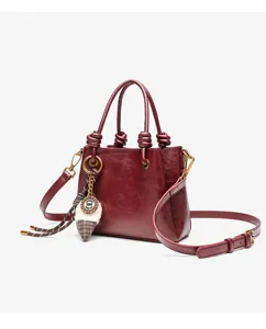 Retro red leather handbag for women, elegant tote bag with chic knot handles and charming charm.