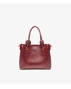 Burgundy leather handbag detail, featuring unique knotted handles and elegant gold-tone hardware.