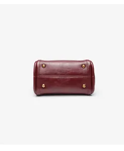 Red leather handbag bottom detail showcasing durable metal feet and neat stitching quality.
