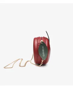Detail view of red apple shaped round cross body bag with green leaf charm and gold chain strap