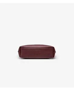 Close-up view of the bottom structure of a minimalist burgundy leather tote bag.
