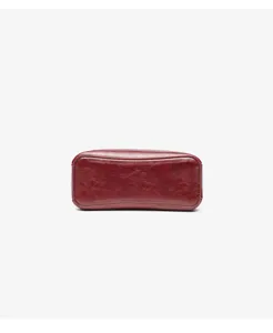 Detailed close-up view of the smooth wine red leather bottom of a stylish retro handbag.