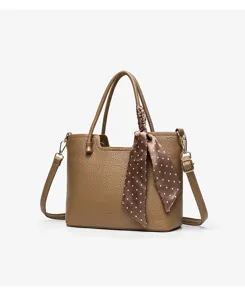 Brown textured leather tote bag detail featuring a chic polka dot silk scarf and handles.