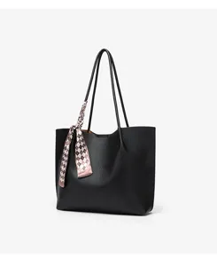 Black leather tote bag detail view with patterned ribbon scarf, minimalist commuter bag.