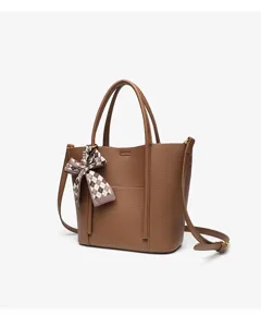 Brown leather tote bag with a chic plaid ribbon bow. Elegant design for women's daily wear.