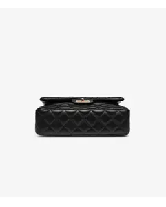 Detail view of black quilted leather shoulder bag with chic metal turn lock and classic pattern.