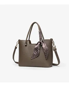 Detail view of stylish brown leather tote bag with elegant polka dot silk scarf accessory.