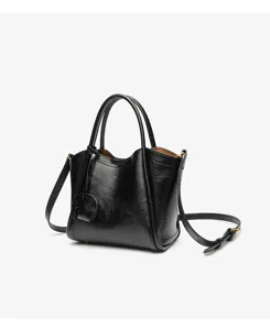 Black leather handbag detail showing fine texture, dual top handles, and durable strap.