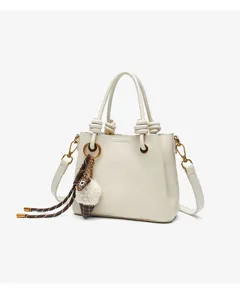 Elegant cream white handbag with knotted handles and cute plush charm for daily chic style.