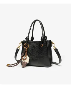 Compact black top handle shoulder bag featuring a cute plush pendant and chic knotted straps.
