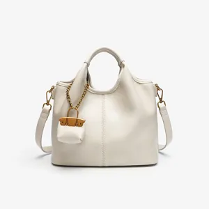 Elegant white leather handbag with top handle and stylish mini bag charm for daily wear.
