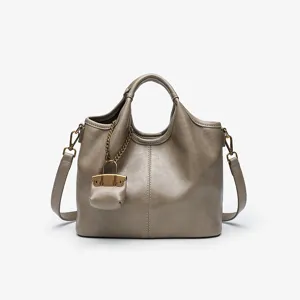 Detailed view of a chic taupe leather bucket bag with a cute mini pouch charm and chain.