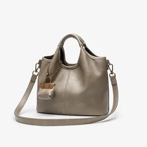 Detailed view of the taupe leather tote bag with metal chain charm and shoulder strap.