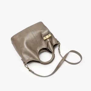 Detailed view of genuine leather bucket bag with top handle and metallic chain strap.