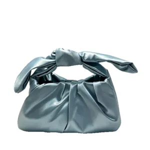 Metallic blue knotted handle women evening handbag, trendy fashion chic design detail.
