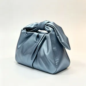 Exquisite metallic blue handbag detail showcasing the stylish knotted handle and pleated texture.