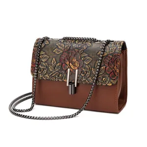 Retro embossed women's crossbody bag with detailed floral flap and metal chain strap.