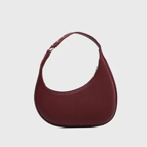 Detail view of the burgundy crescent hobo bag featuring fine pebbled leather texture and hardware.