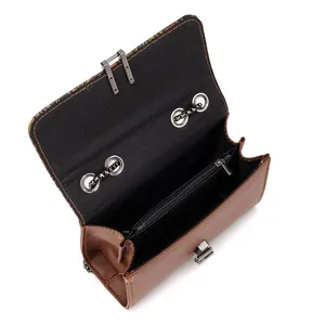 Detail view of brown leather women's shoulder bag with metallic lock and zipper pocket inside.
