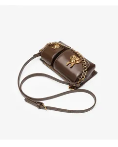 Detailed close-up of brown leather shoulder bag with gold chain and unique rabbit metal decor.