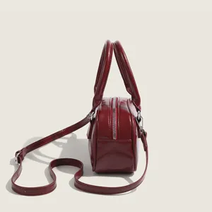 Closeup side view of a red patent leather bowling bag with top handles and adjustable strap.