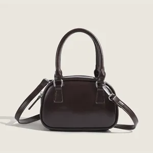 Detailed view of the dark brown bowling handbag with top handles and metal hardware.