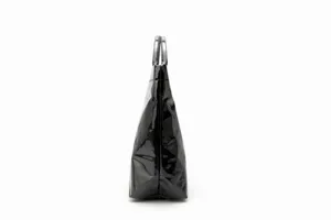 Side view detail of black glossy patent tote bag showing slim profile and handles.
