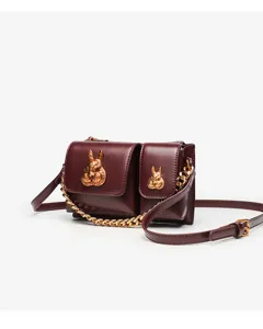 Detailed shot of the dark red shoulder bag featuring golden rabbit heads and chain strap.