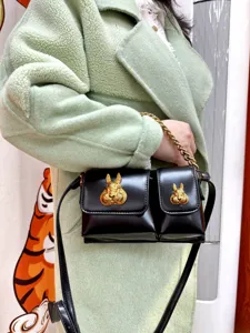 Black PU leather crossbody bag with metal chain and golden 3D rabbit head decor for women.