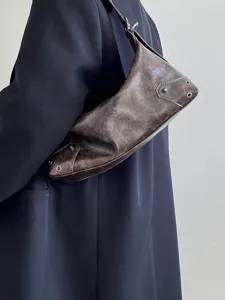 Vintage brown underarm bag detail shot showing distressed leather texture, metallic eyelets and rivets.