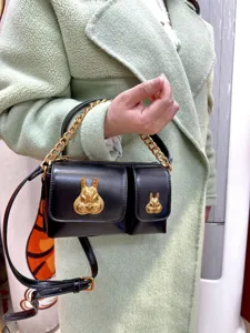 Detail view of a black leather motorcycle bag featuring stylish gold-tone rabbit head accents.